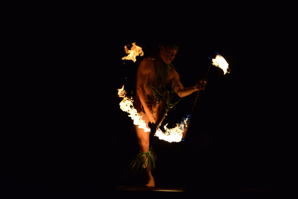 A captivating fire dancer performing a traditional Hawaiian dance at night.