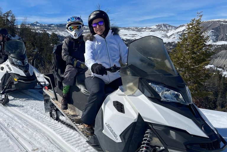 Two people on snowmobiles in the snow